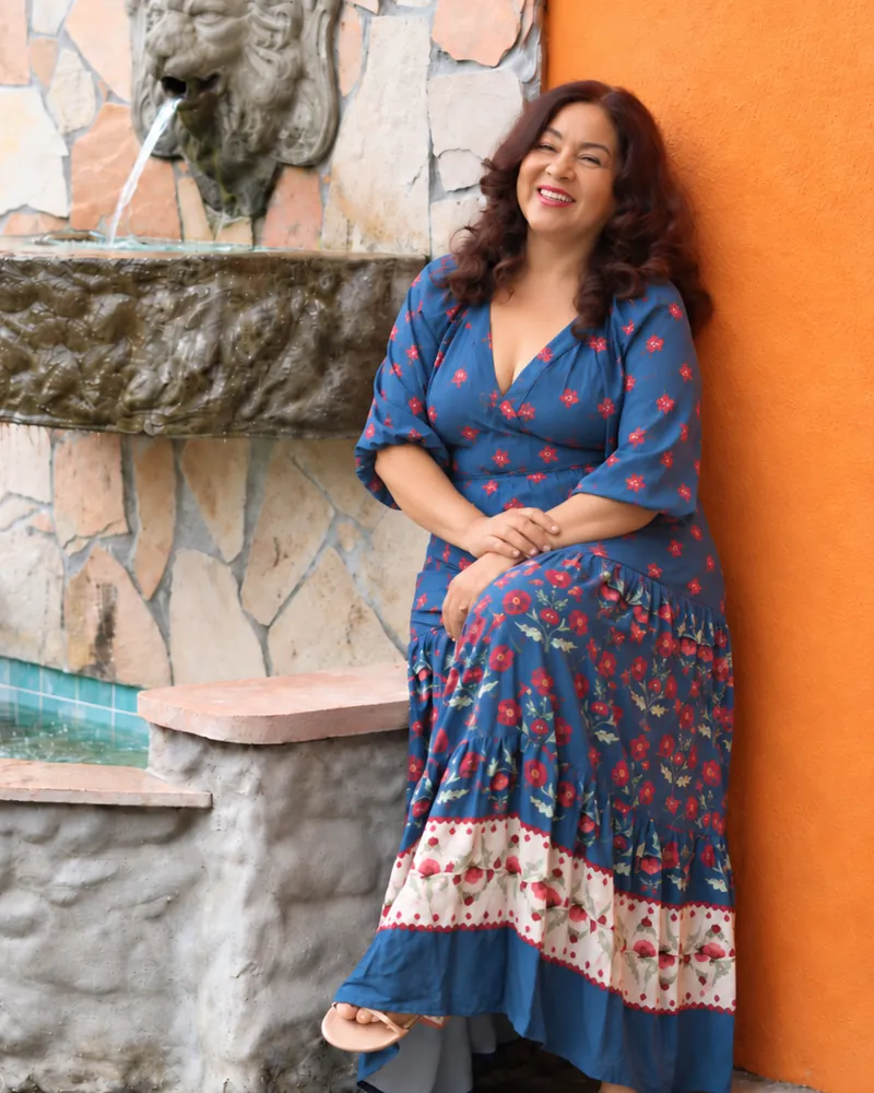 Carlla Almèida sorrindo ao lado de uma fonte